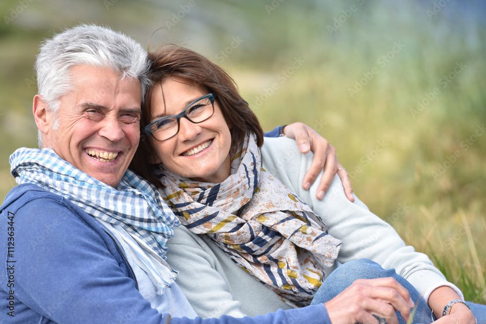 Cheerful senior couple sitting in grass Cheerful senior couple sitting in grass