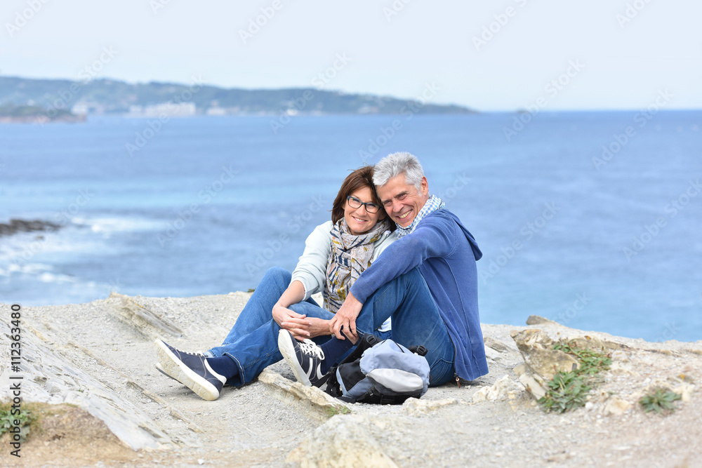 Senior couple on rambling day sitting by cliff