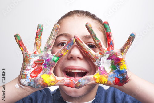 Little student girl showing painted hands on grey background © cristovao31