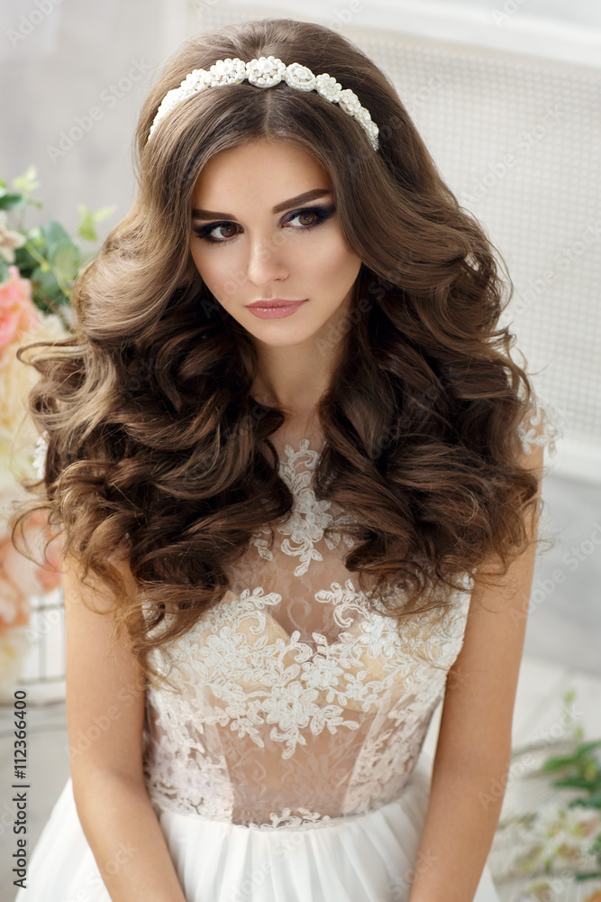 Beautiful woman portrait with curly hair in white dress. Young lady posing with flowers. Bride Beautiful woman portrait with curly hair in white dress. Young lady posing with flowers. Bride