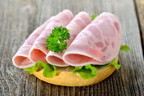 Garniertes Brötchen mit Schinkenwurst, Salatblatt und Petersilie - Open faced sandwich with sliced ham sausage and lettuce leaf