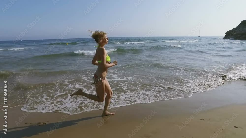 A beautiful girl runs on the beach in her bikini A beautiful girl runs on the beach in her bikini