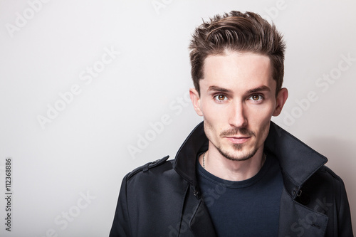 Bild auf Leinwand Elegant young handsome man in long stylish dark blue coat