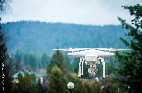 white quadrocopter with camera in mountains and beautiful landscape on the background