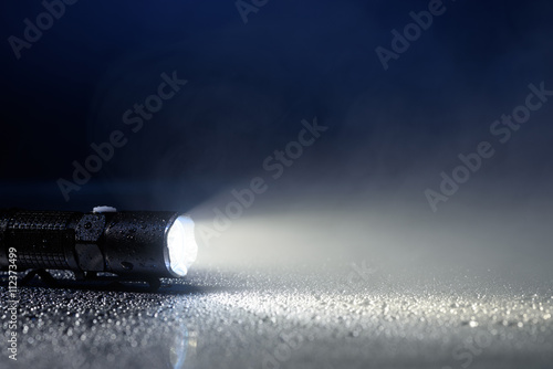 Tactical waterproof flashlight with water drops and fog photo