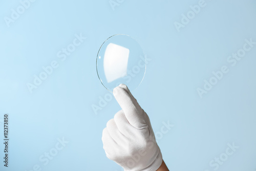 New features glass or plastic research, hand in glove holding circle piece of transparent material