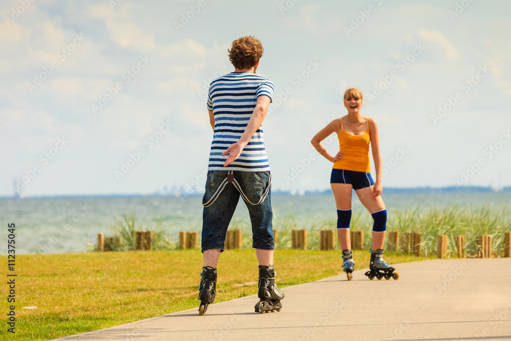 Fototapeta premium Young couple on roller skates riding outdoors