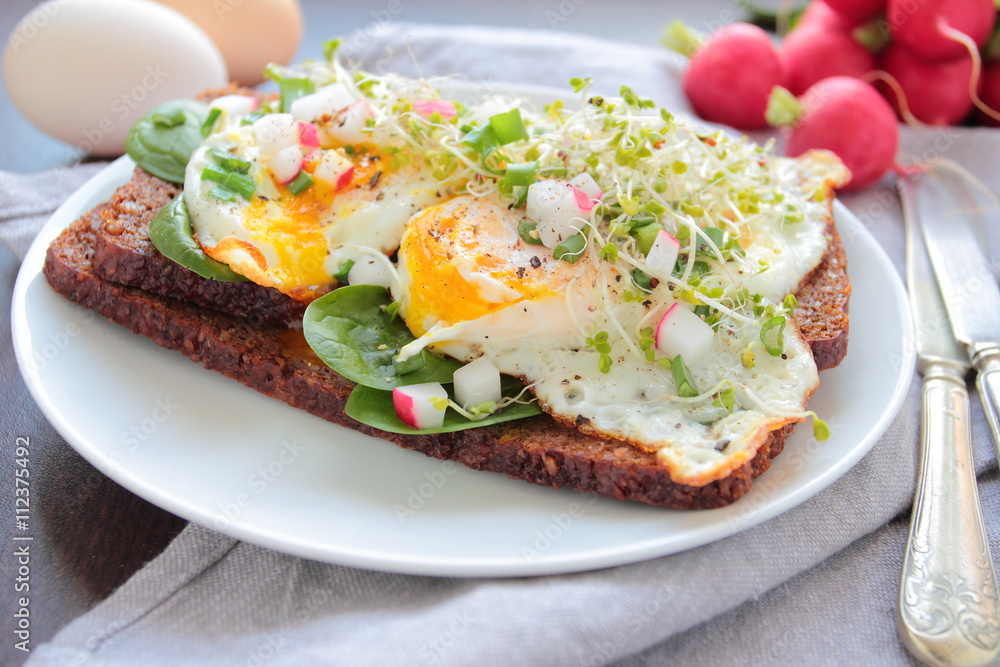 Poached eggs with fresh vegetables on a dark bread