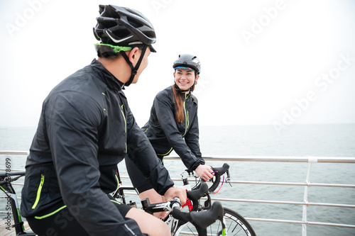 Couple on bicycle resting and talking near sea