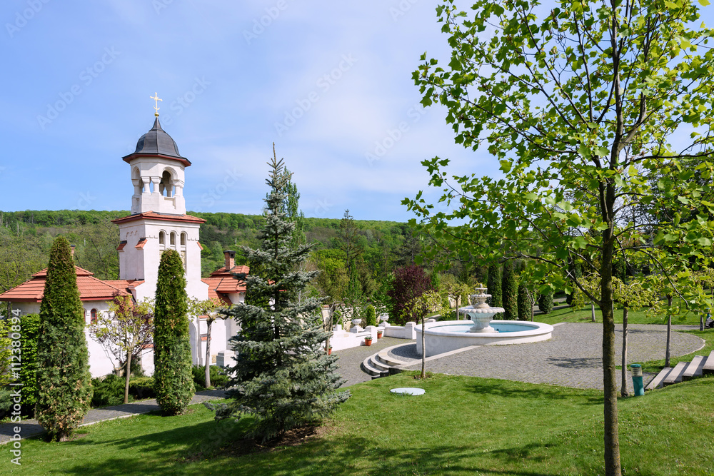 Bell tower and basin at orthodox Curchi monastery in Moldova with green trees and blue sky Bell tower and basin at orthodox Curchi monastery in Moldova with green trees and blue sky