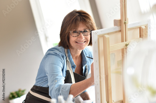 Senior woman painting on canvas