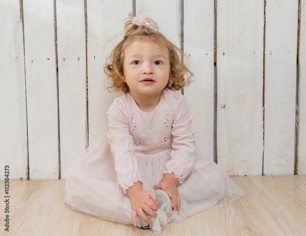 funny stylish little girl in fluffu skirt sitting on the floor in wooden studio funny stylish little girl in fluffu skirt sitting on the floor in wooden studio