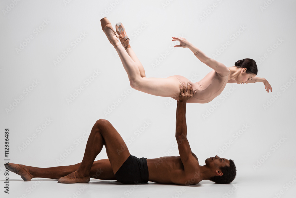Fototapeta premium Couple of ballet dancers posing over gray background
