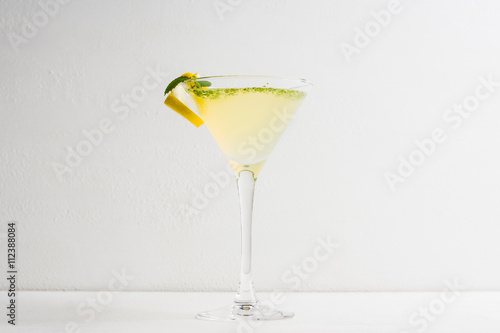 Yellow martini cocktail with lemon and mint on the rustic wooden background