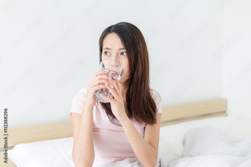 Woman drink water and sitting on bed Woman drink water and sitting on bed