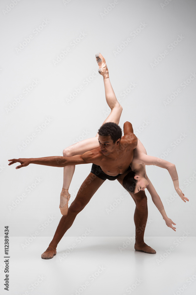 Fototapeta premium Couple of ballet dancers posing over gray background