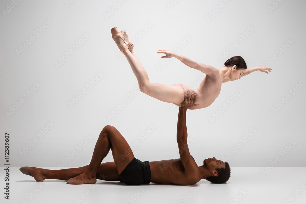 Fototapeta premium Couple of ballet dancers posing over gray background