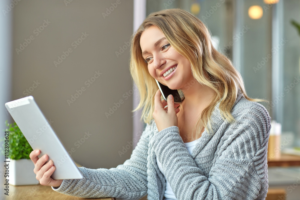 Beautiful young woman holding laptop and talking on the phone at the cafe. Freelancer Beautiful young woman holding laptop and talking on the phone at the cafe. Freelancer