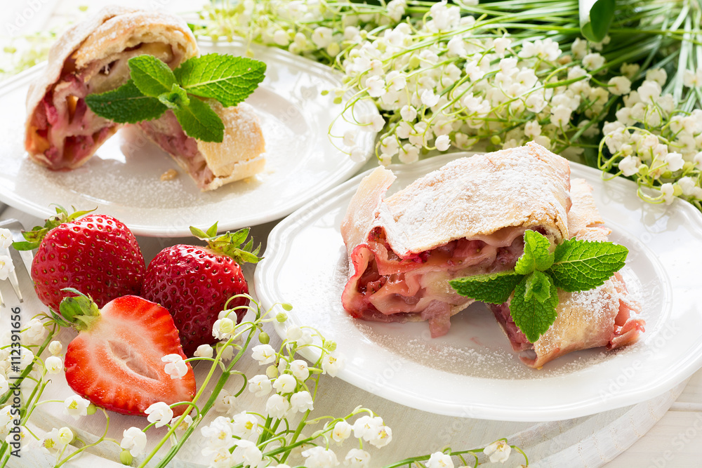 Homemade strudel with strawberries decorated mint leaves  on white wooden background
