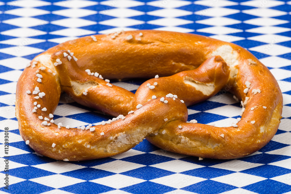Single Bavarian pretzel with german flag on blue and white rhombus napkin Single Bavarian pretzel with german flag on blue and white rhombus napkin