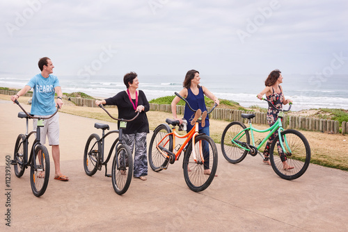 Healthy family walking along the ocean side pushing bicycles