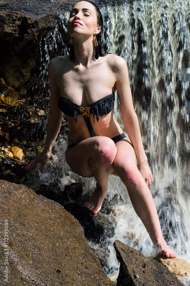 beautiful woman in black swimsuit enjoying a waterfall