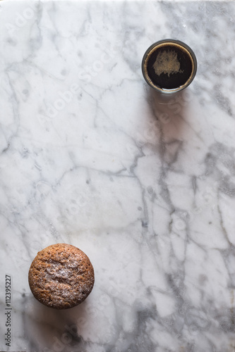 Cup of coffee in a glass and a cake over marble background. Top