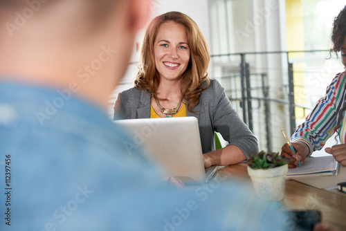 Free Download Multi ethnic group of succesful creative business people using a laptop during candid meeting - GFXLoad