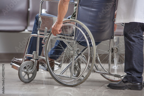 man's arm pushing wheel of wheelchair