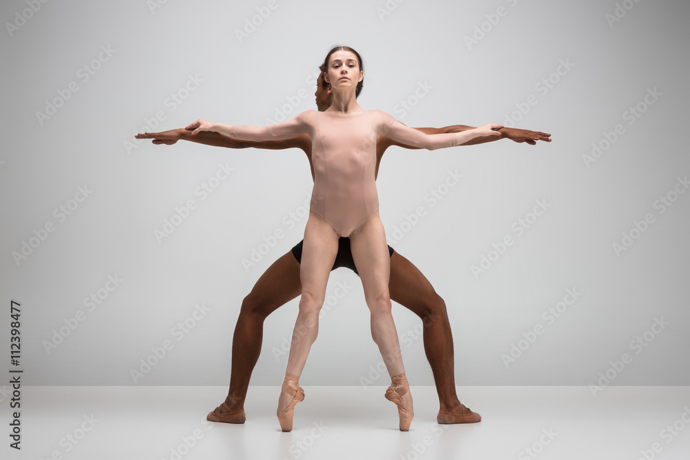 Fototapeta premium Couple of ballet dancers posing over gray background