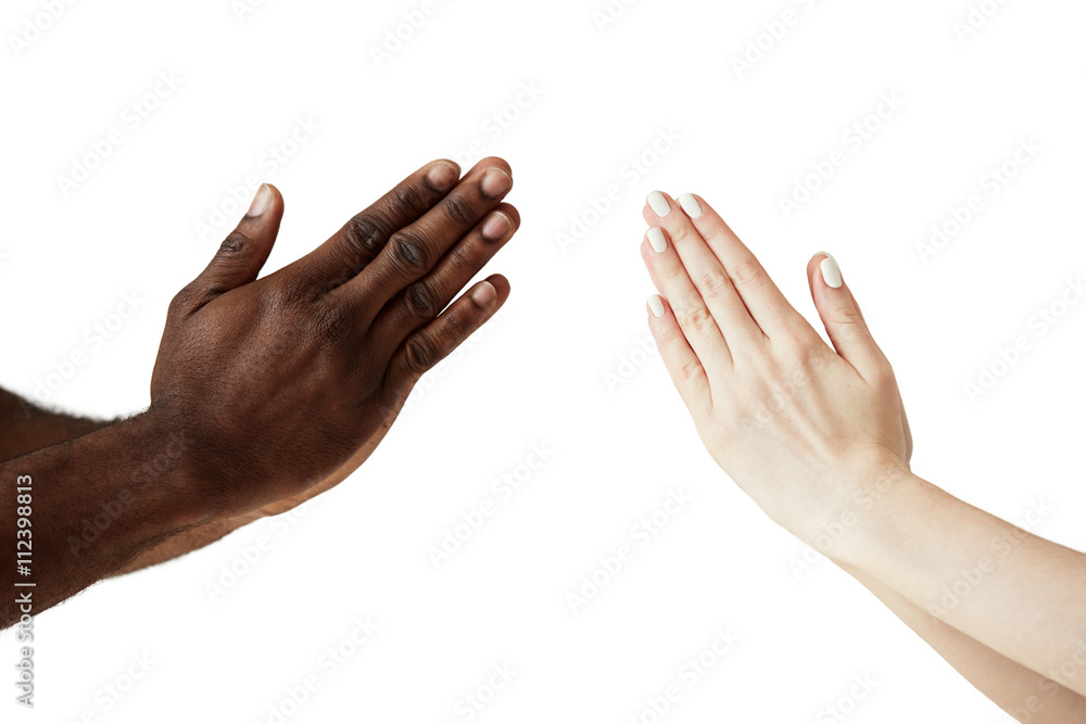 Two people of different races and ethnicities holding hands in namaste, greeting each other against white studio wall background. Multicultural and interracial cooperation and friendship concept