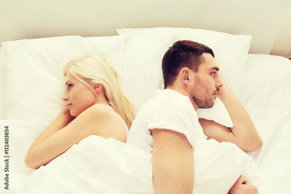 unhappy couple lying in bed at home unhappy couple lying in bed at home