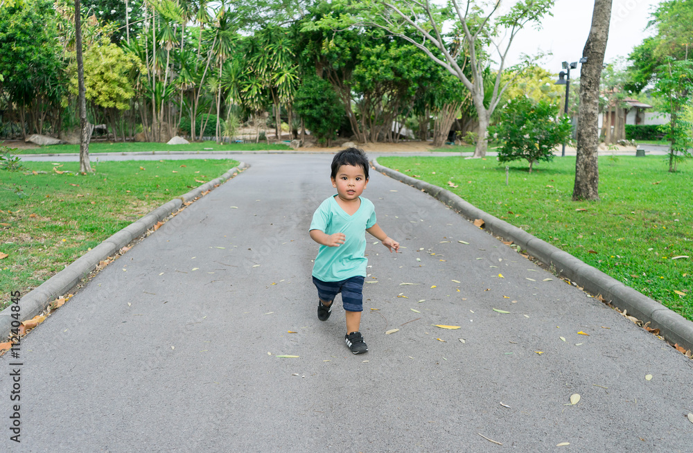 Little Boy running in a park or garden among trees Little Boy running in a park or garden among trees