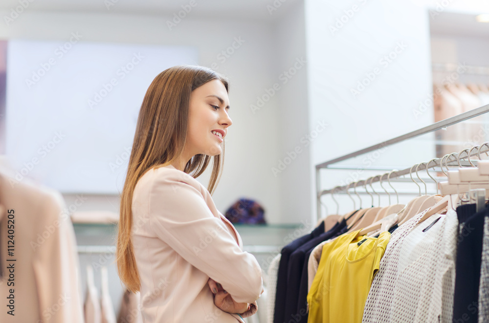 Obraz premium happy young woman choosing clothes in mall