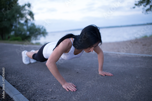 Sporty woman push up at river in twilight