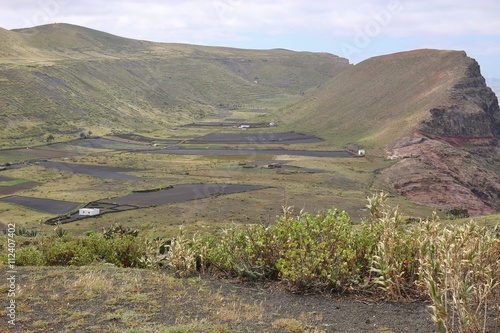 Farm houses on North Lanzarote beneath the Famara cliffs. The fields are  covered with lava soil. Near Guinate, Lanzarote, Canary Islands, Spain. photo