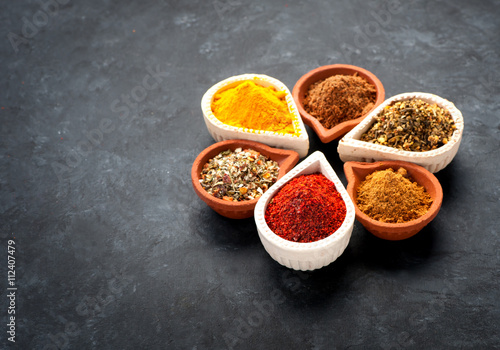 Spices, herbs and spicy spices in bowls on a black background