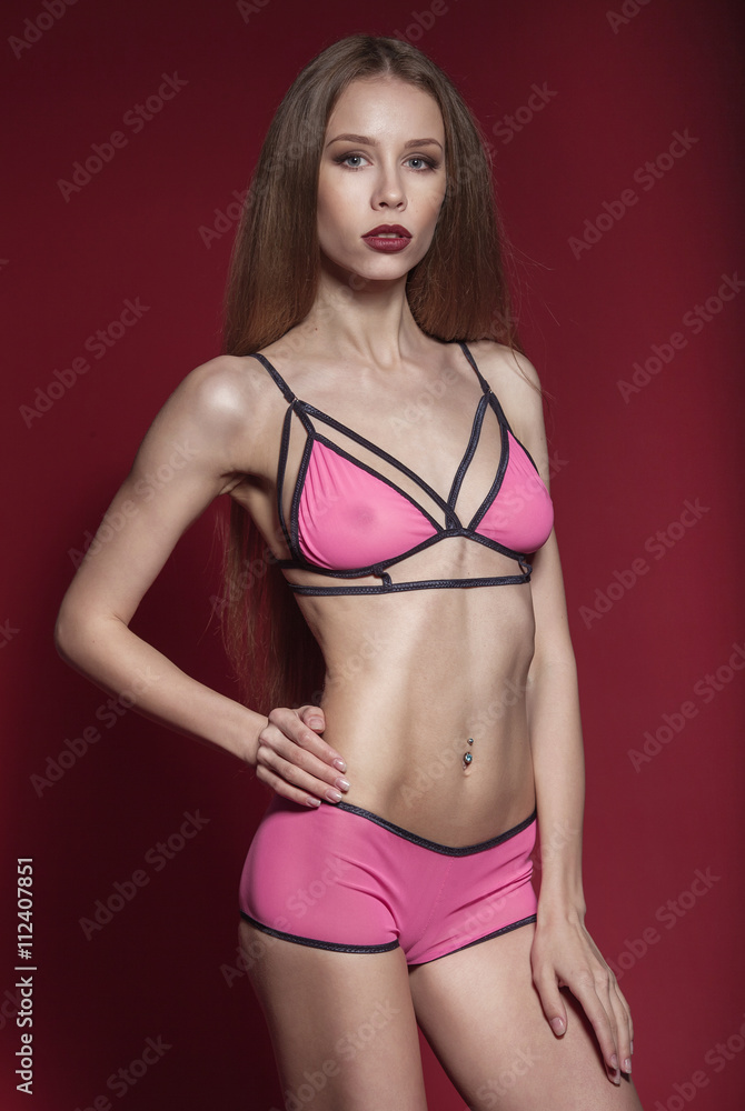 Sexy woman in  lingerie on red background, fashion studio shot.