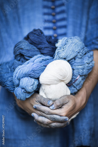 A man holding balls of wool dyed with natural indigo color