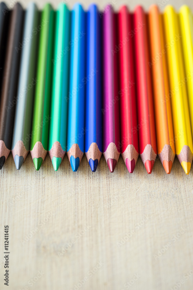 Fototapeta premium Color Pencils on wood texture. Macro shot of colorful pencils. Vertical view of pencils.
