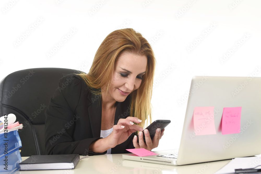 businesswoman working at laptop computer office desk sending text message on mobile phone businesswoman working at laptop computer office desk sending text message on mobile phone