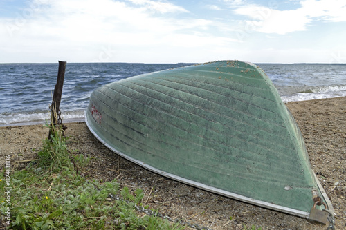inverted boat on the shore of a large lake .