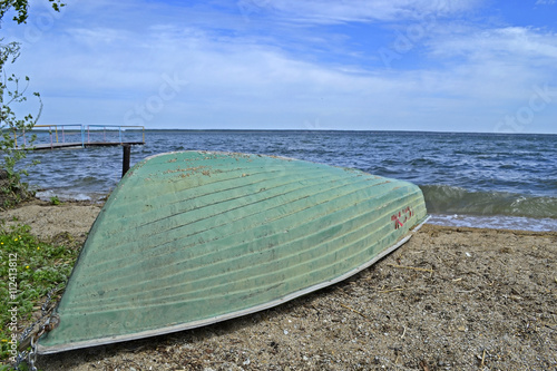 inverted boat on the shore of a large lake .