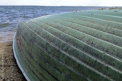 inverted boat on the shore of a large lake .