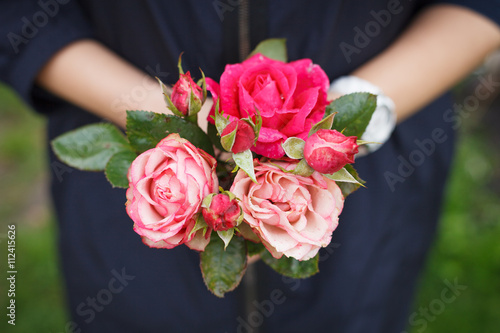 Closeup of woman's hand holding beautiful bunch of garden roses. View from above, selective focus on flowers.