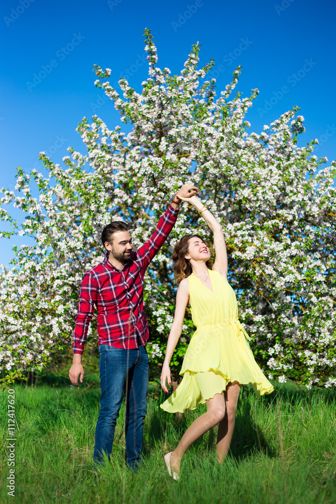 Fototapeta premium young beautiful couple in love dancing in blooming garden