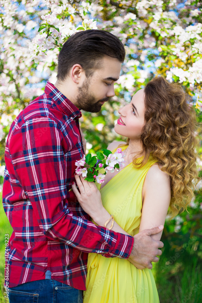 young man embracing happy girlfriend in garden