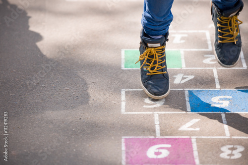 Closeup of boy's legs and hopscotch drawn on asphalt. Child playing hopscotch on playground outdoors on a sunny day. outdoor activities for children. photo