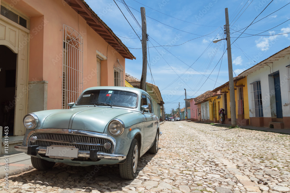 Classic american car parked on a typical cobblestone road in Trinidad, Cuba