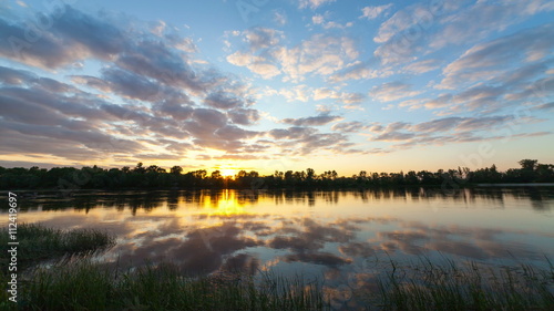 clouds over a bog with plants and a tree. Time-lapse a sunset with bright clouds